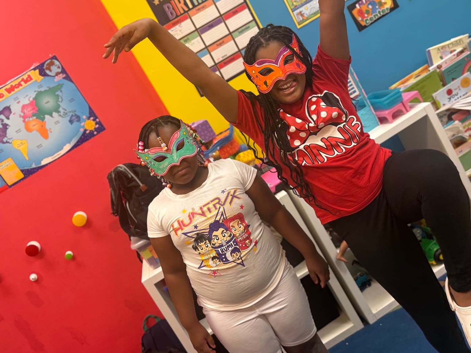 Two children laughing together while wearing handmade paper masks