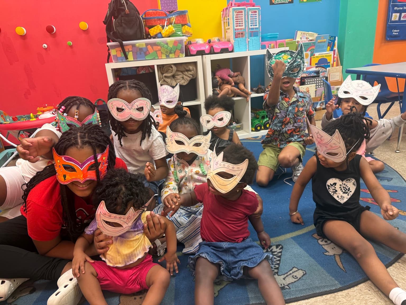 A large group of children posing together in colorful handmade paper masks