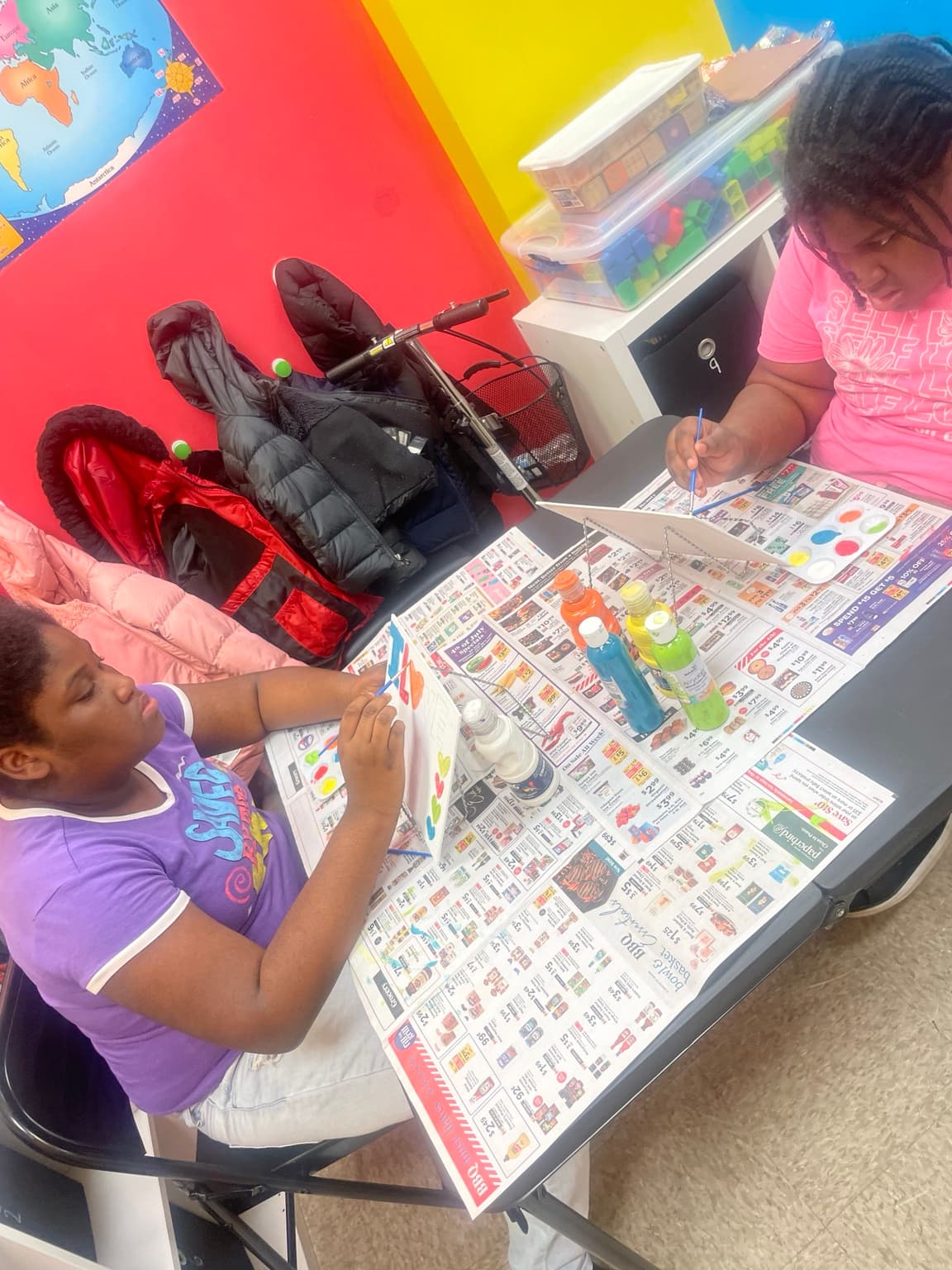 Two children concentrating while painting pictures at a table